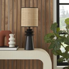 a table lamp sitting on top of a white shelf next to a potted plant