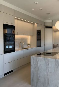 a modern kitchen with marble counter tops and white cabinets, along with an island in the middle