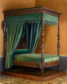 an antique four poster bed with green drapes