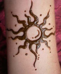 a sun tattoo on someone's arm that is black and white with brown spots