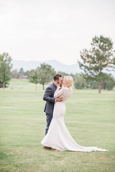 a bride and groom kissing in the grass