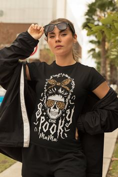 a woman wearing sunglasses and a black shirt is walking down the street with her hand on her head