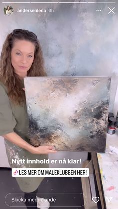 a woman holding up a large painting in front of her face with the caption