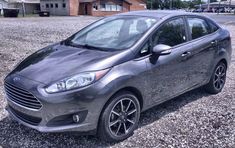 a gray car parked on top of a gravel road