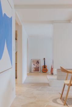 an empty room with a guitar on the wall and other furniture in the background,