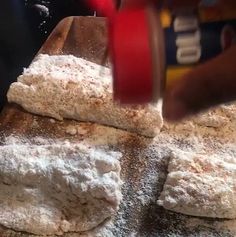 some food is being made on top of a wooden cutting board with flour sprinkled all over it