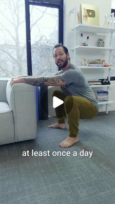 a man is doing yoga on the floor in front of a white couch and window