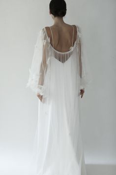 the back of a woman wearing a white dress with sheer sleeves and an open back