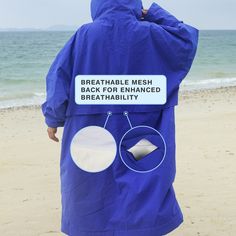 a person in a blue coat standing on the beach with their back to the camera