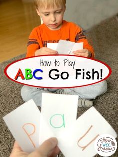 a young boy sitting on the floor playing with letters that spell out how to play abc go fish