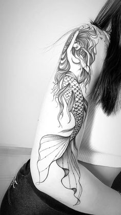 a woman with a fish tattoo on her back and shoulder is sitting in front of the camera