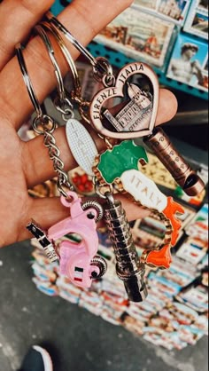 a person holding several different key chains in their hand with various charms on them,