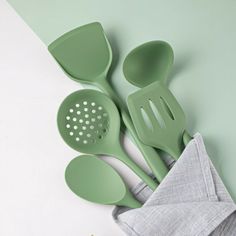 three green kitchen utensils sitting next to each other on top of a cloth