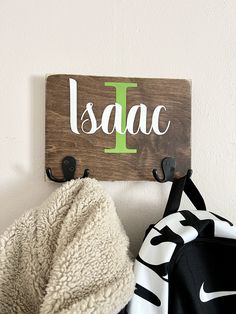 a coat rack with two coats hanging from it's hooks, and a personalized sign on the wall