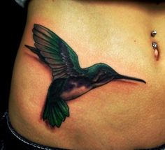 a hummingbird tattoo on the side of a woman's stomach