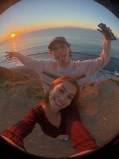 two people are taking a selfie with the sun setting in the background