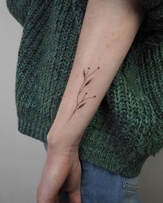 a woman's arm with a small flower tattoo on it