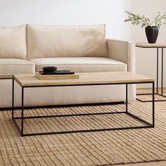 a coffee table sitting on top of a rug in front of a couch and end tables