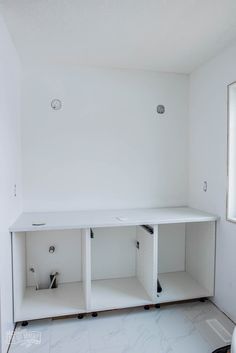 an empty room with white shelving in it