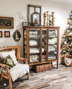 a living room with a christmas tree in the corner and a china cabinet next to it