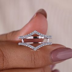 a woman's hand holding a diamond ring in front of her face and the other hand