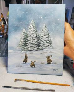 a painting of two rabbits sitting in front of a snowy pine tree with snow falling on the ground