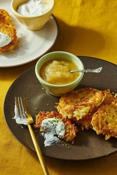 some food is on a black plate with a yellow table cloth and two bowls of sauce