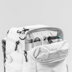 the back pocket of a white backpack with various items in it's pockets and zippers