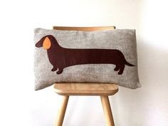 a pillow with a dog on it sitting on a wooden chair next to a white wall