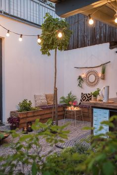 an outdoor patio with lights strung from the ceiling and potted plants on the table