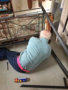 an older man laying on the ground next to a bed and some screwdrivers