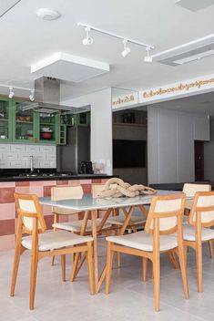 a dining room table and chairs in a kitchen with green cupboards on the wall