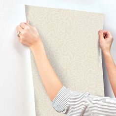 a woman is painting a wall with white paint