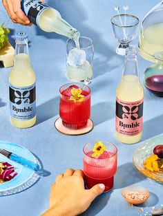 a person pouring drinks into glasses on a table with plates and bowls full of food