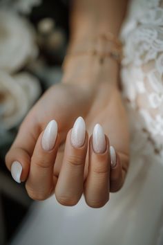 a woman's hand with white manicures on her nails and lace dress