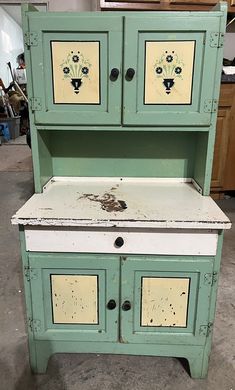 an old green cabinet with two doors and drawers