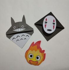 three pieces of paper that have been cut out to look like animals and faces on them