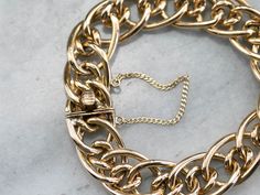 This chunky chain bracelet has an impressive weight to it! Crafted of fine 18 karat gold, this piece is a real showstopper and certainly a status symbol. The uniquely designed links interlock in a stylish way, and have an exceptionally bright polish. A strong box clasp and safety chain ensure security when worn. Metal: 18K Yellow Gold Width: 16 mm Length: 7 Inches Marks: "18K" Stamped on the clasp Status Symbol, Heavy Chain, Cameo Ring, Safety Chain, Box Clasp, Yellow Gold Bracelet, July Birthstone, Statement Bracelet, Eternity Bands