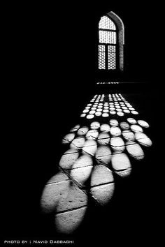 the shadow of a window is cast on cobblestones in front of an arch