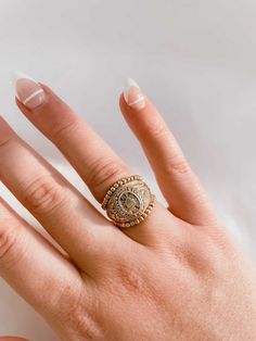 a woman's hand with a gold ring on top of her finger and white manicured nails