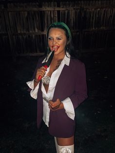 a woman with green hair and white stockings holding a pipe in her mouth while standing next to a fence