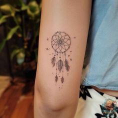 a woman's arm with a small dream catcher tattoo on the left inner arm