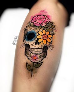 a woman's arm with a colorful skull and flower tattoo on the left thigh