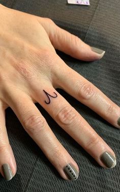 a woman's hand with a small tattoo on her left thumb and ring finger