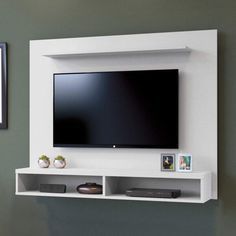 a flat screen tv mounted to the side of a white wall next to a mirror