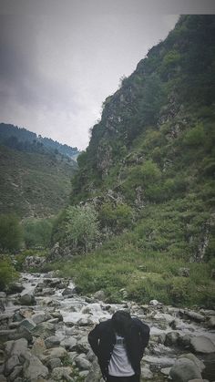 a person standing on rocks in the middle of a stream