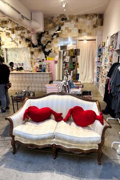 a white couch with red pillows on it in a room filled with books and other items