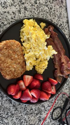 breakfast plate with eggs, bacon, strawberries and toast