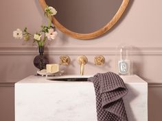 a bathroom sink with a towel on it and a mirror above it that has flowers in the corner