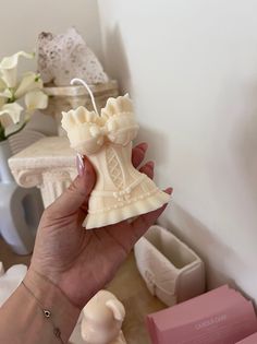 a hand holding a small white vase shaped like a dress